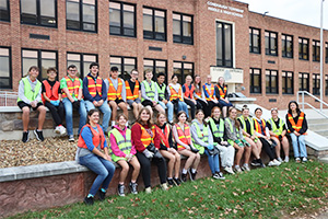 Group of students wearing safety vests outside school building