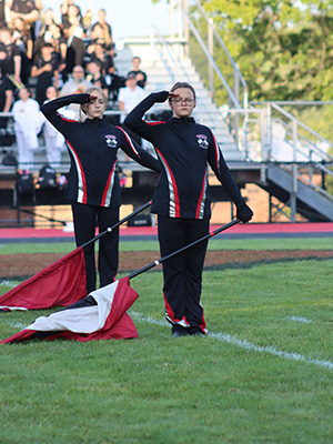 two students saluting with color guard flags