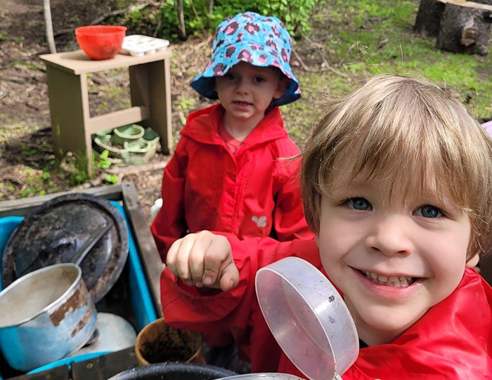 Two students smiling for the camera from a campsite