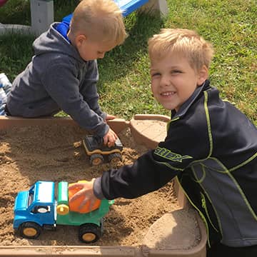 Two boys playing with trucks in the sand