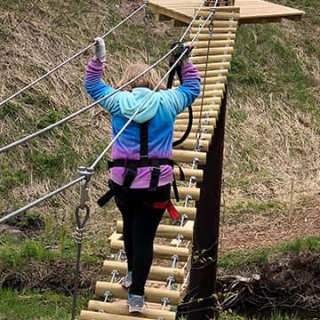 Student in winter wear walking across bridge