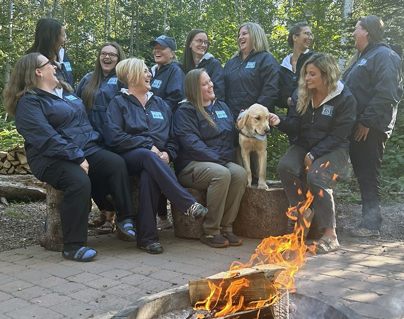 Birch Grove staff sitting in camp chairs out in the woods