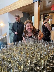 Smiling woman by table of champagne glasses
