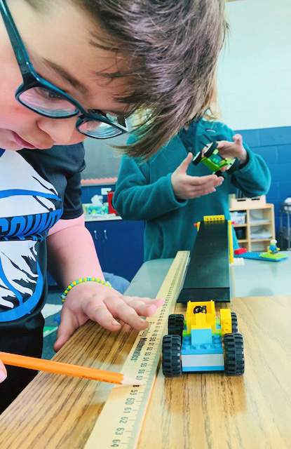 Young student measuring a truck with a ruler