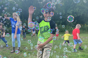 Student playing with bubbles on the grass