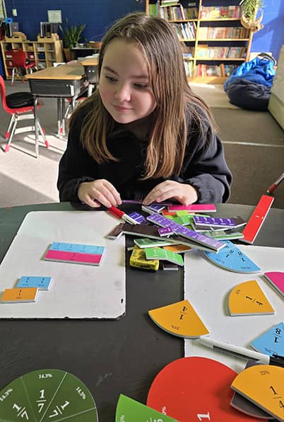 Young girl working with fraction puzzle pieces