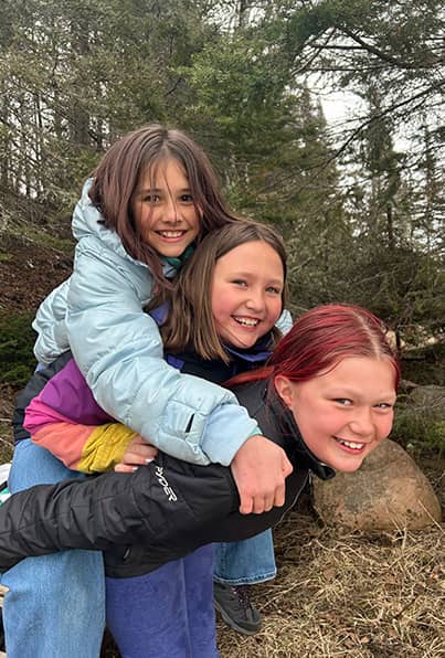 Three girls outside piggyback