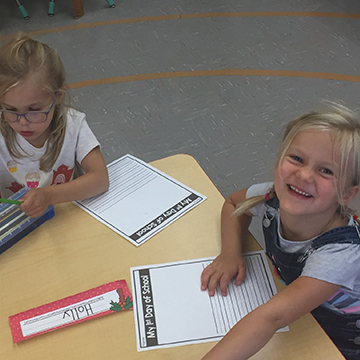 Two girls smiling at a table in class