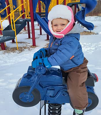 Seedling playing outside on rocking horse