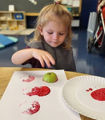 Little girl with apple and paints