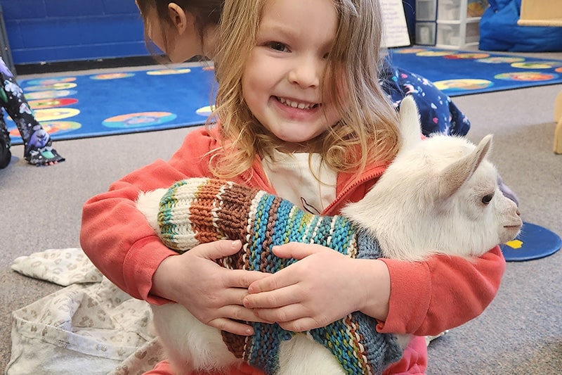 Happy girl holding a goat