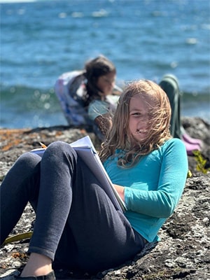Girl sitting on the sand by the lake