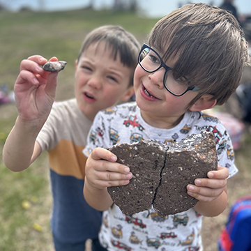 Closeup of two boy examining a piece of rock outside
