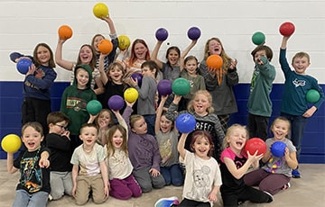 Students holding colored balls in the air