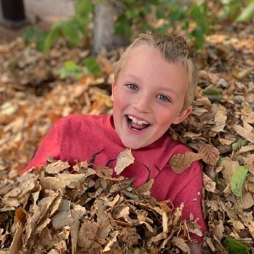 Happy boy playing in the leaves outside