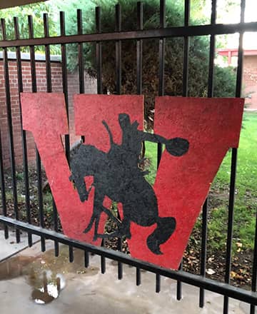 A W with a cowboy painted on it placed on a fence
