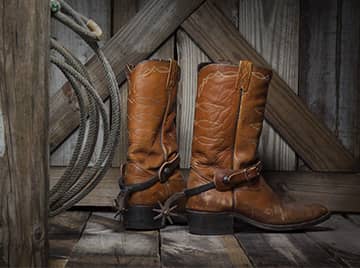 A pair of cowboy boots next to a lasso