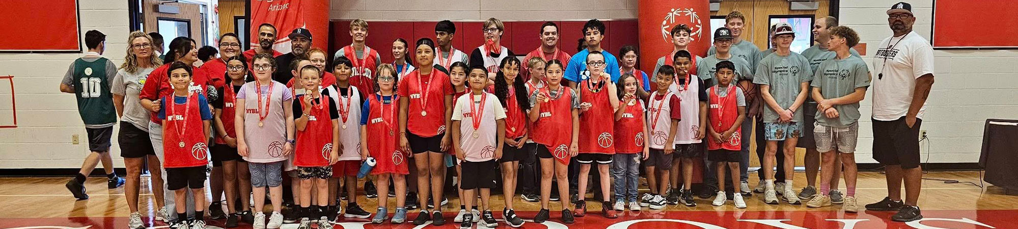 Students and couches standing in the gym with medals