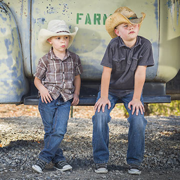 Two boys in cowboy hats sitting on a truck Two boys in cowboy hats sitting on a truck