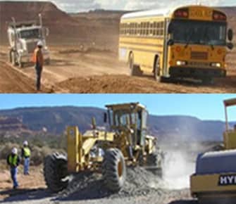 Heavy road equipment and school bus on dirt road