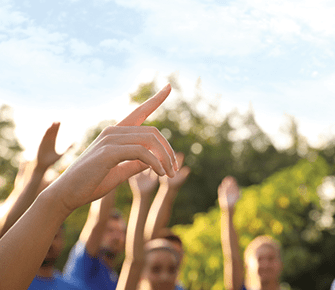Group of adults raising their hands outside