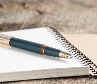 Fountain pen on top of a spiral notebook