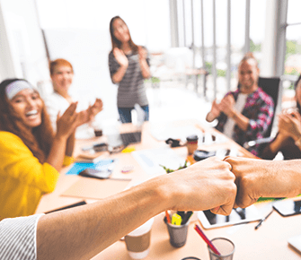 group of coworkers fist bump in team meeting