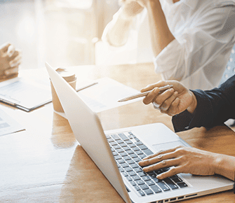 Coworkers working together while looking at a laptop