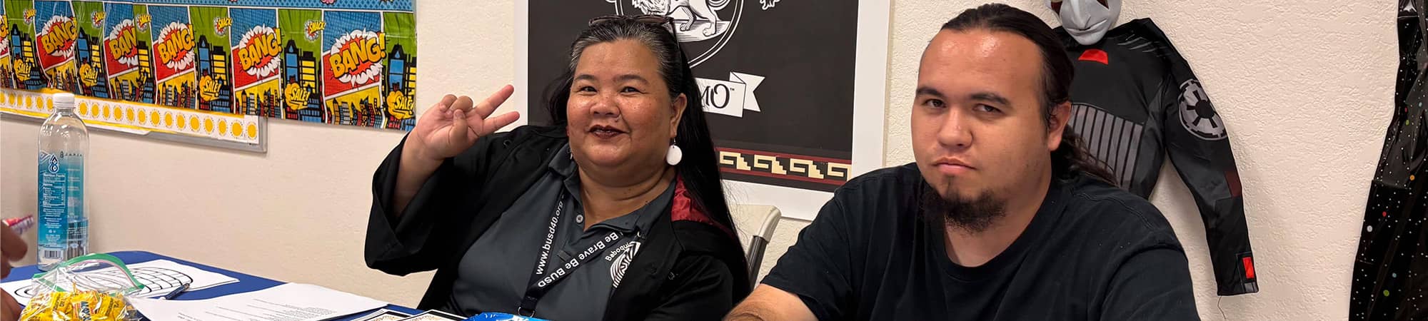 Staff sitting at a table, one is giving a peace sign
