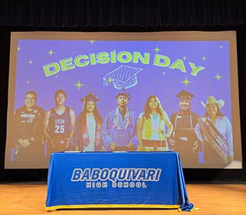 table with a tablecloth reading Baboquivari High School in front of a screen titled Decision Day with students in different careers