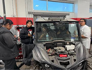 Students in and around a car with no hood