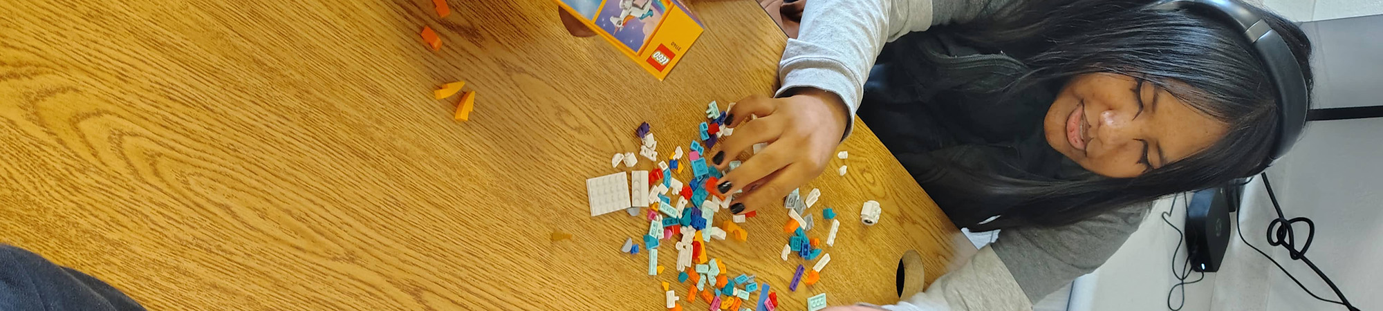 A student with headphones putting Legos together