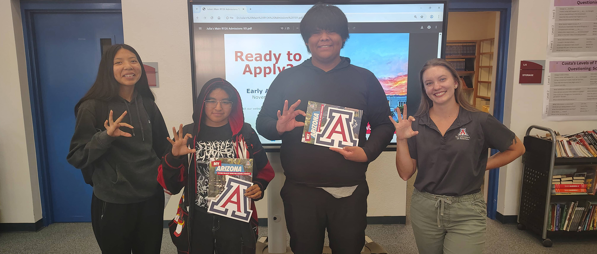 Students next to adults while making the University of Arizona “Wildcat” hand sign and holding University brochures