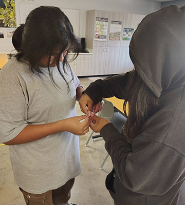 Two students working together on something very tiny