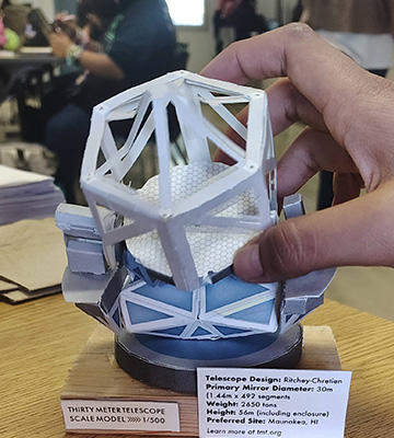 A hand holding a Thirty Meter Telescope scale model