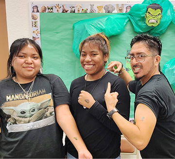 An adult pointing at two students showing the tattoos