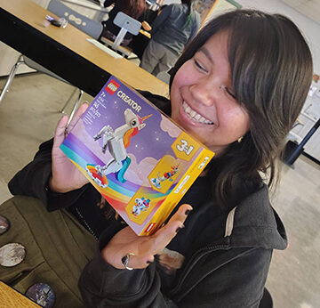 A student holding up a Unicorn Lego kit