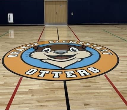 Orange Elementary Otters logo in the middle of they gym floor