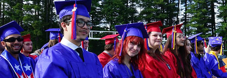 Students sitting on the bleachers with their graduation caps and gowns