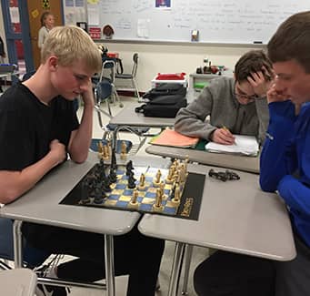 two students playing chess in class