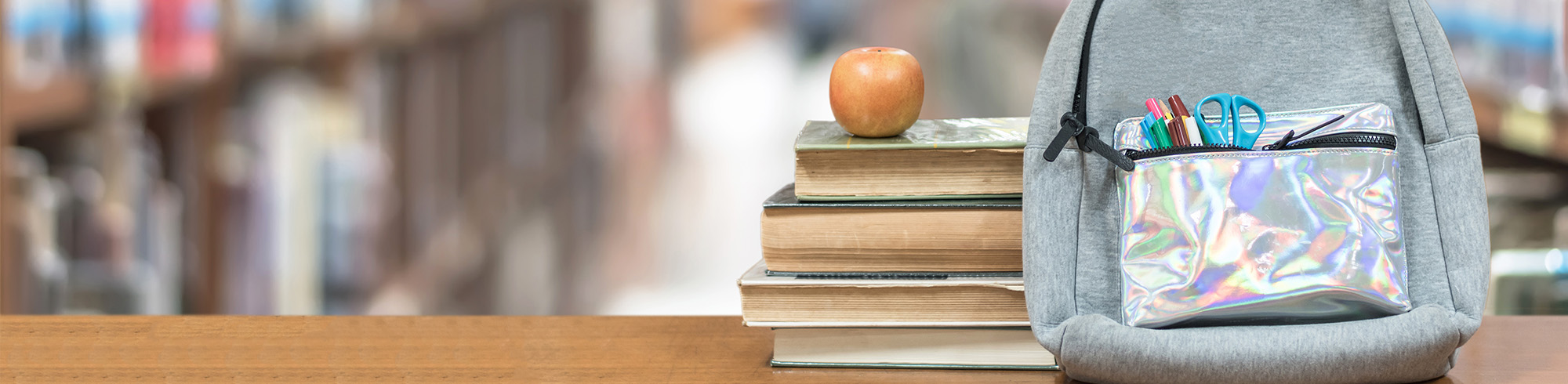 Stack of books with apple and backpack