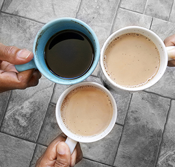 Three adults holding up coffee cups