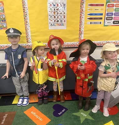 pre-k students dressed in costumes of firefighters, construction worker, and a police officer
