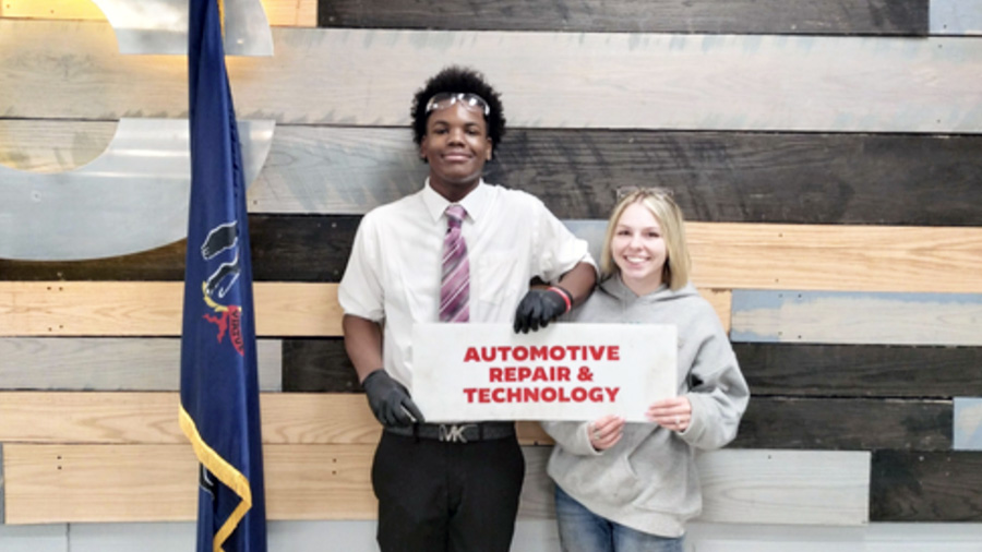 Two students proudly holding an Automotive Repair & Technology sign