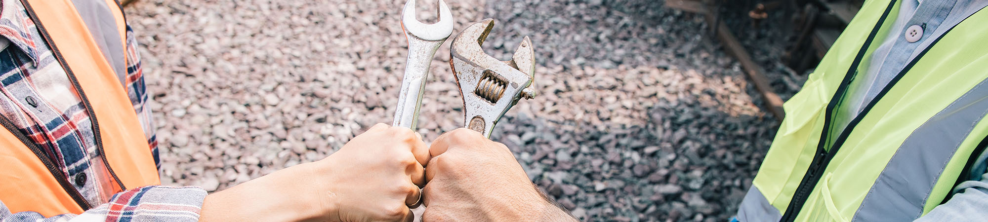Two construction people giving each other a fist bump with wrenches in their hands