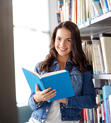 Happy female student looking up from a blue book