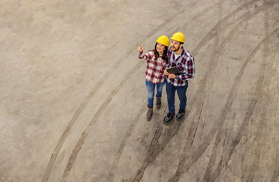 Two construction workers looking up from a construction site