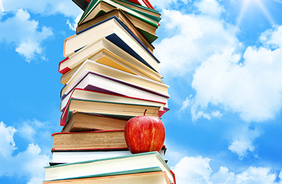 Pile of books and apple next to blue sky