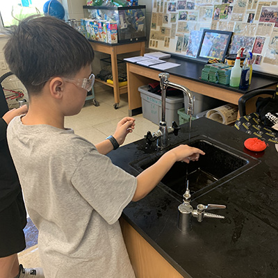 boy wearing safety goggles and washing at a sink