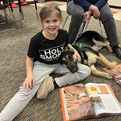 girls sitting with dog while she reads